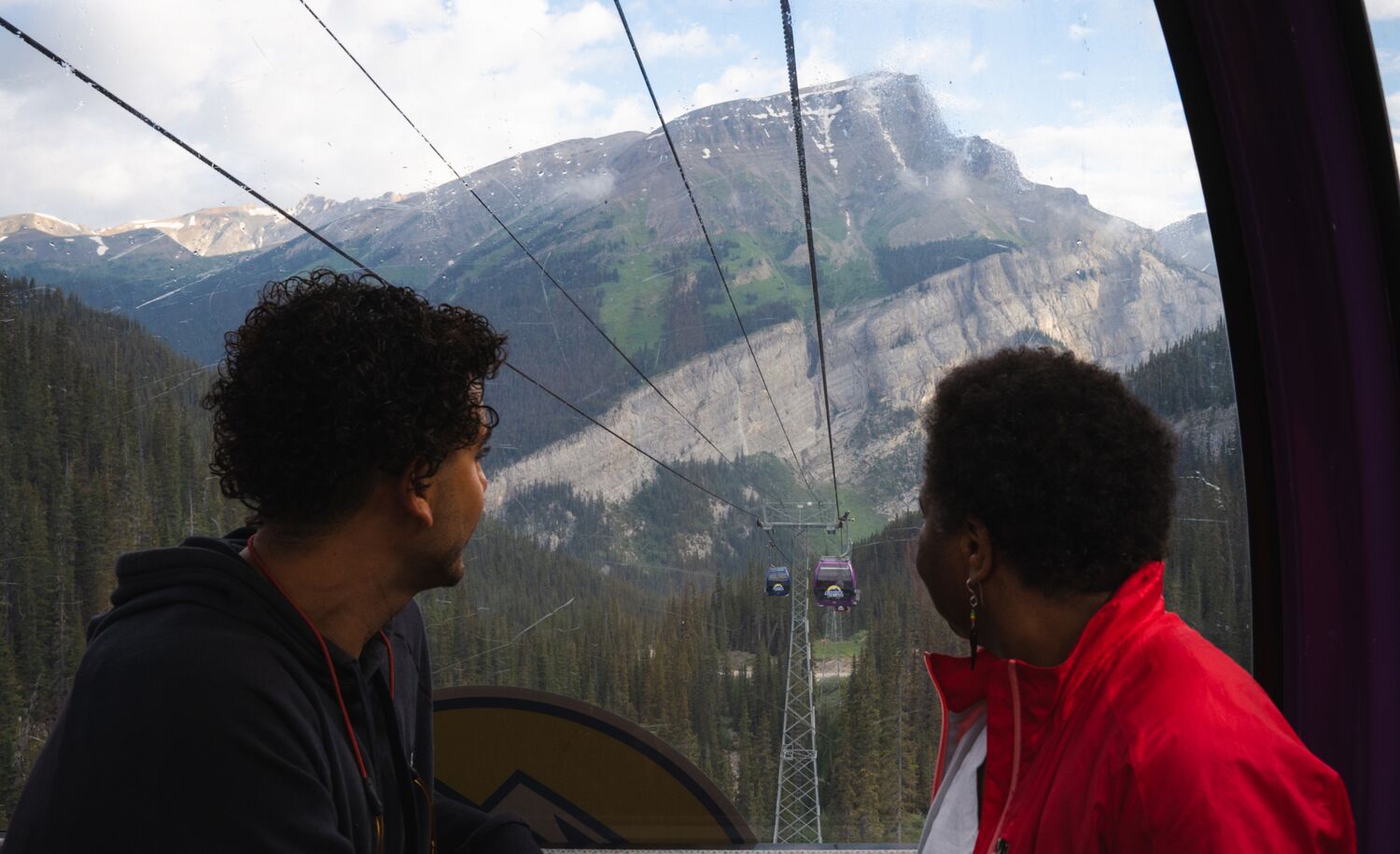 Two people look out of a gondola window towards a mountain at Banff Sunshine Village.
